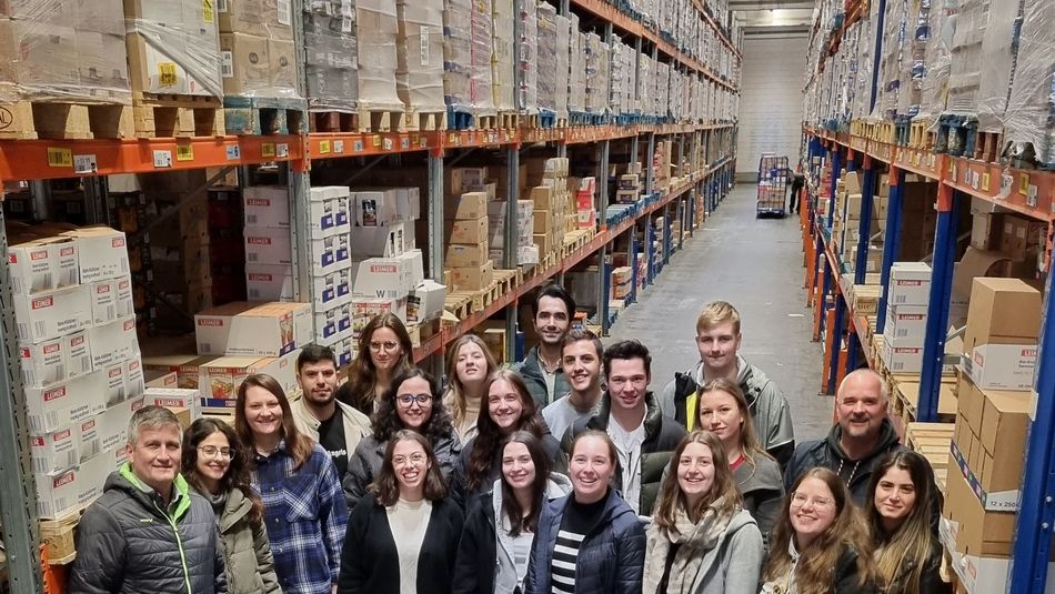 Studierende der Lebensmitteltechnik der Hochschule Trier stehen als Gruppe im Zentrallager von EDEKA zwischen Hochregallagern