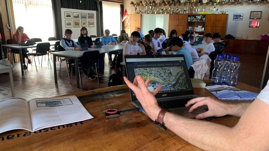 Laptopansicht mit Schüler*innen im Hintergrund